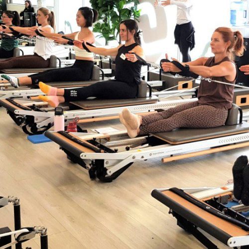 a row of people doing pilates workouts on a studio